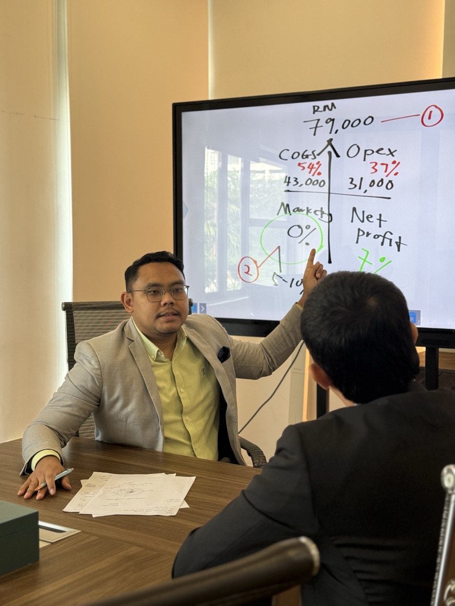 Consultant menerangkan pecahan kos dan net profit di skrin